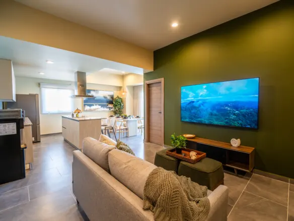 Sala de estar con pared verde y TV en departamento Akoya Sky Living