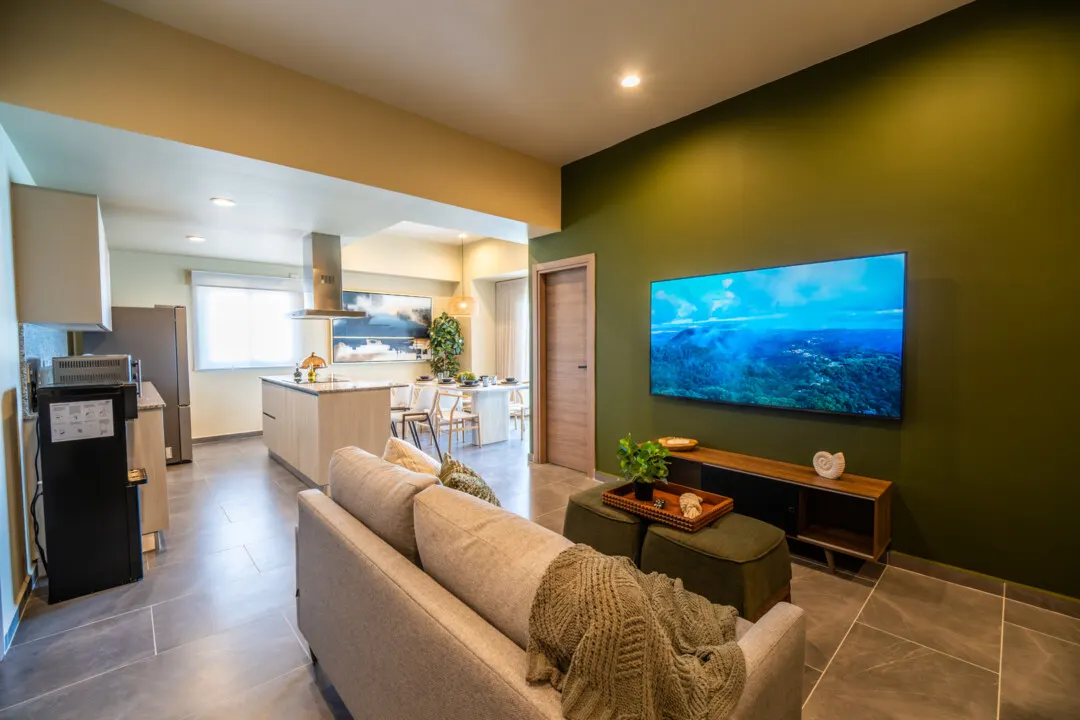 Depa Akoya Renta Fer-68 Sala de estar con pared verde y TV en departamento Akoya Sky Living
