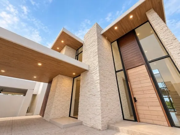 Fachada de casa en venta en El Cid, Mazatlán, con techo inclinado de madera y muro de piedra
