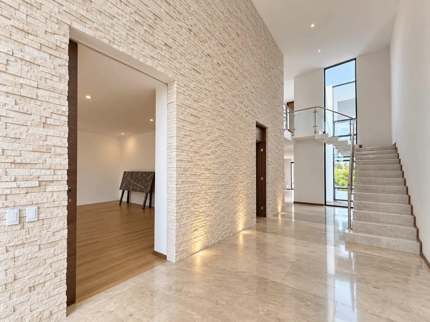 casa-venta-el-cid-mazatlan-vista-marina25 Recibidor con muro de piedra, escalera y piso de mármol