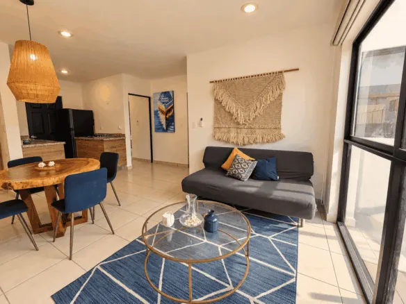 Sala con sofá, mesa de centro y comedor de madera en departamento amueblado en venta en Mazatlán
