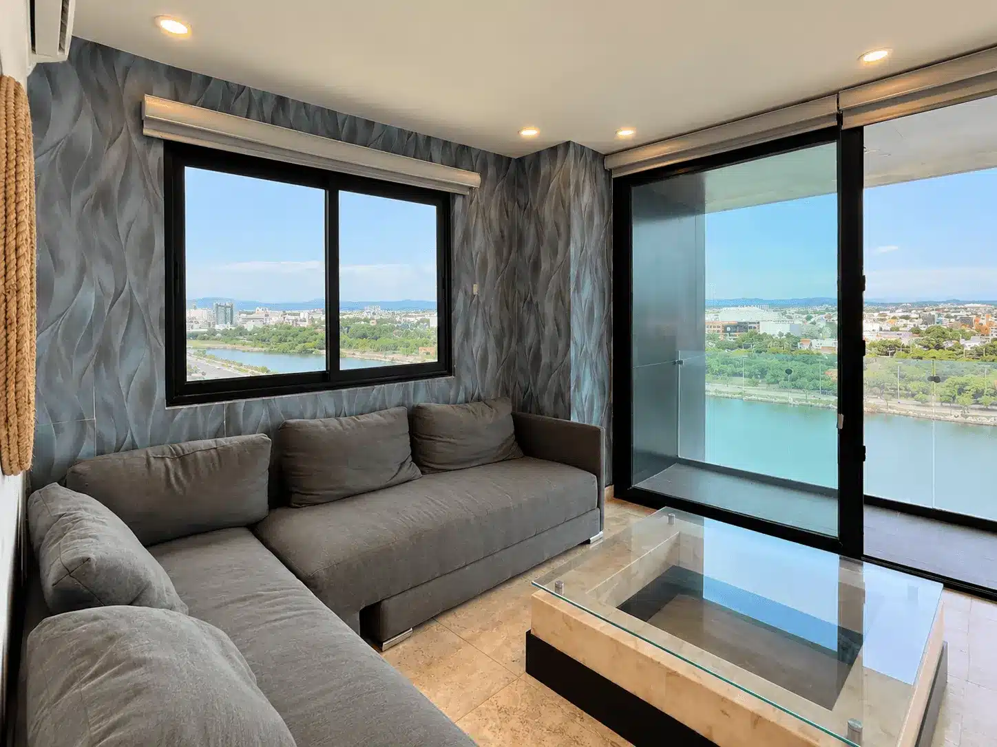 departamento-venta-malecon-central-102-mazatlan-bienes-raices23 Sala con sofá gris y vista panorámica a la laguna, departamento en venta Malecón Mazatlán