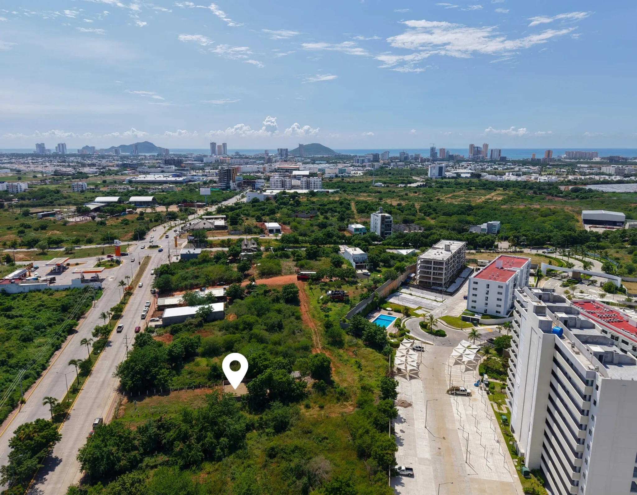 terreno-venta-villa-universidad-galerias-mazatlan-luis10 Ubicación del terreno en venta en Marina Universidad, Mazatlán, señalada sobre vista aérea con edificios cercanos