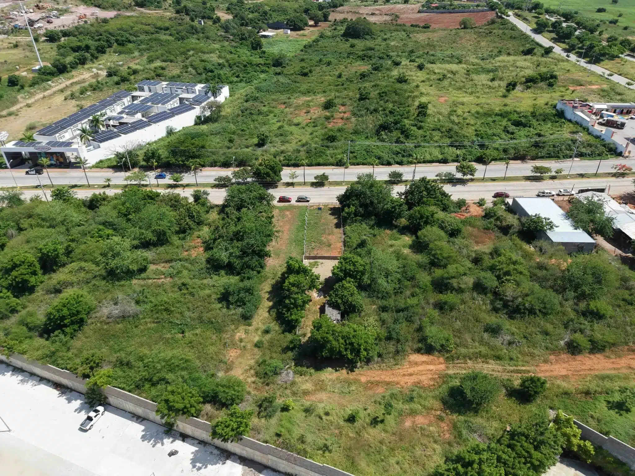 terreno-venta-villa-universidad-galerias-mazatlan-luis2 Vista aérea del terreno en Marina Universidad con vegetación y vialidad de acceso