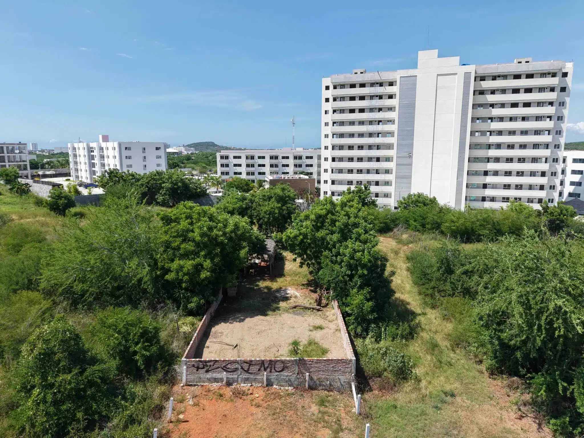 terreno-venta-villa-universidad-galerias-mazatlan-luis3 Vista aérea del terreno en esquina en Marina Universidad, Mazatlán, con edificio residencial al fondo