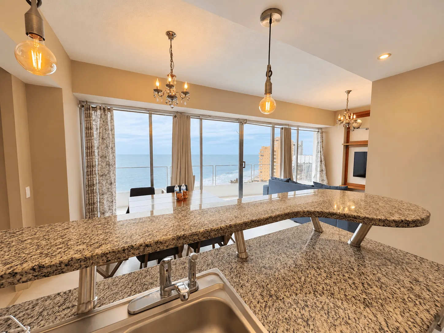 departamento-park-royal-mazatlan-cerritos-vista-al-mar-playa20 Barra de granito con fregadero y ventanales con vista al mar en la cocina de un departamento en Park Royal Mazatlán