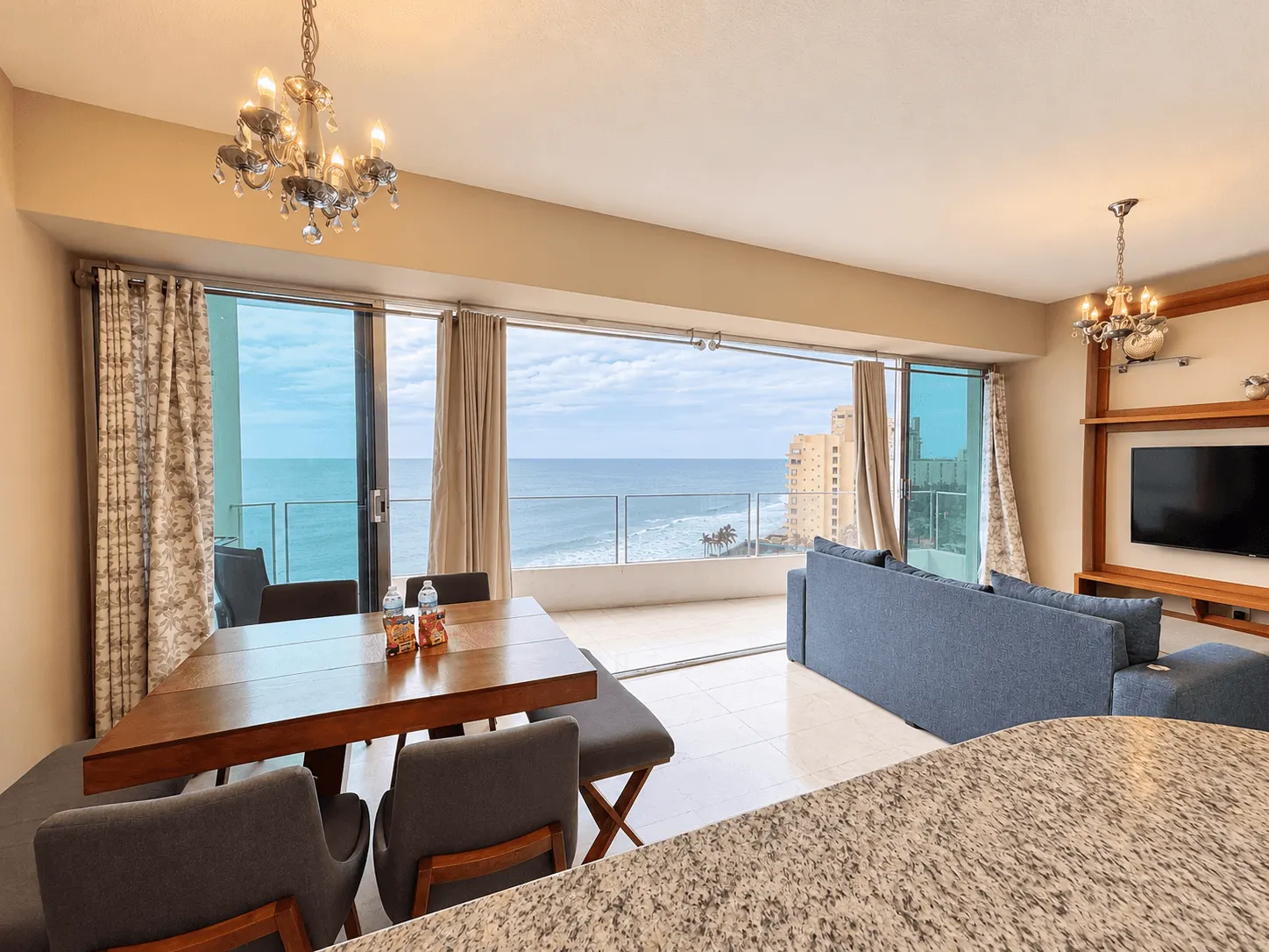 departamento-park-royal-mazatlan-cerritos-vista-al-mar-playa21 Comedor de madera y sala con candil y puertas corredizas hacia la terraza con vista al mar en Park Royal Mazatlán