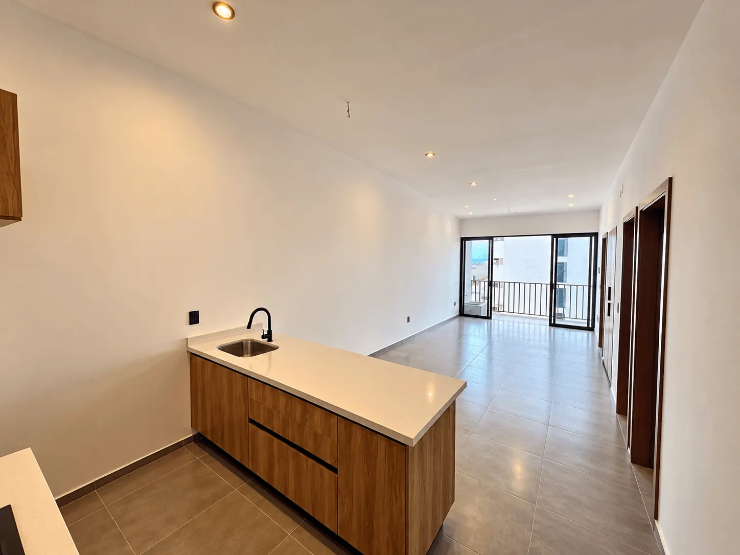 departamento-san-sebastian-palos-prieros-en-venta-mazatlan-malecon-12 Cocina con barra y sala con ventanal al fondo, departamento a estrenar en Palos Prietos