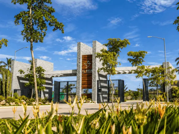 Entrada del fraccionamiento El Cielo Parque Residencial rodeada de palmeras y áreas verdes